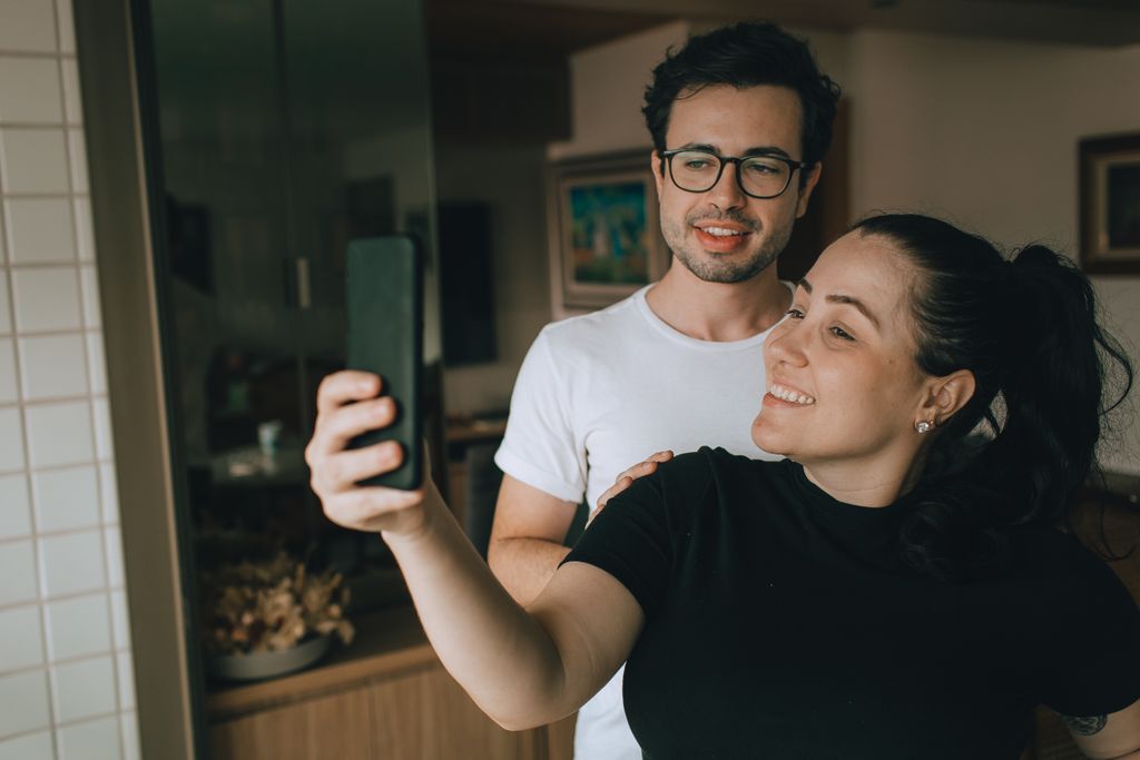 A cheerful couple captures the moment with a selfie indoors, highlighting their joyful connection.