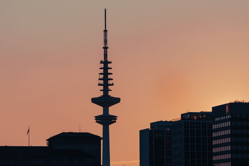 Silhouetted view of a city skyline featuring a TV tower at sunset, exuding urban serenity.