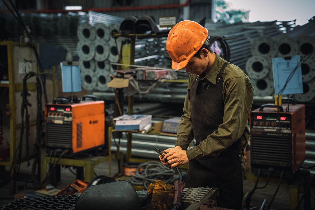 A factory worker wearing safety gear operating machinery in an industrial setting.