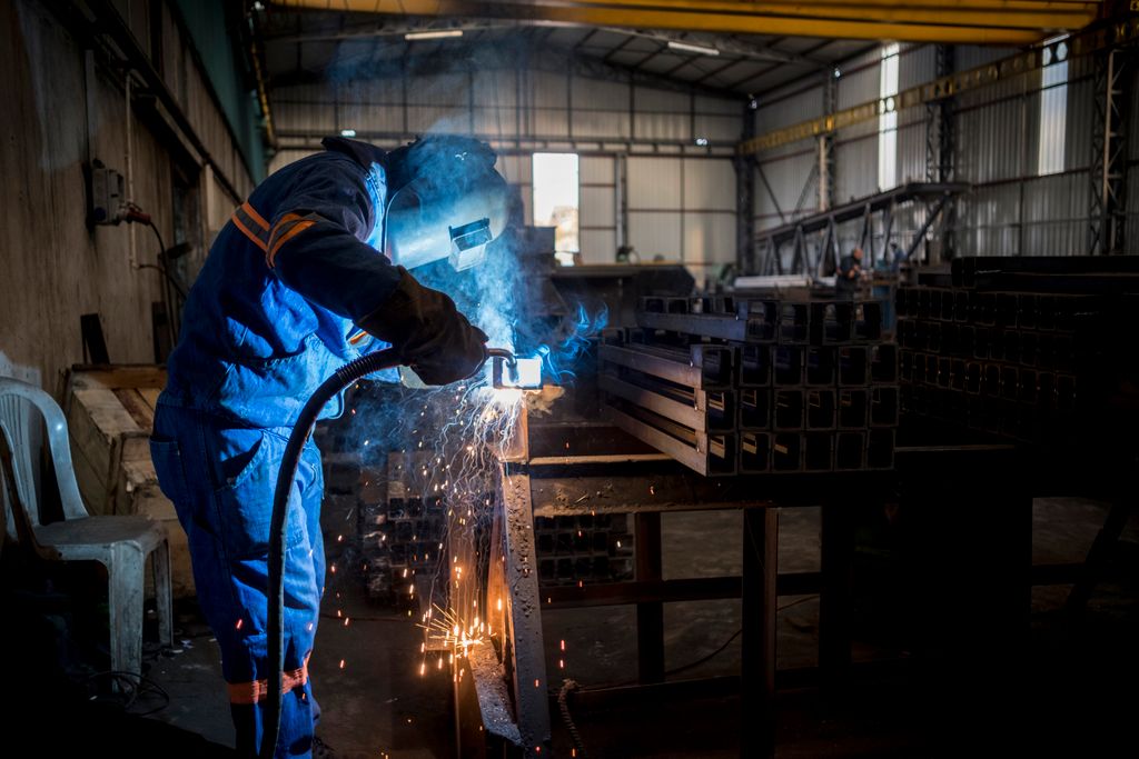 A welder at work inside a manufacturing facility in Adana, Türkiye. Sparks fly during the process.