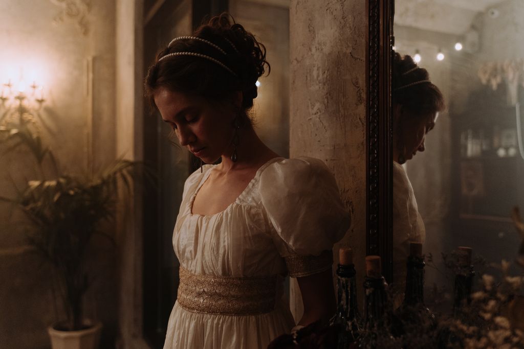A woman in regency attire reflecting in a mirror, depicting classic elegance.