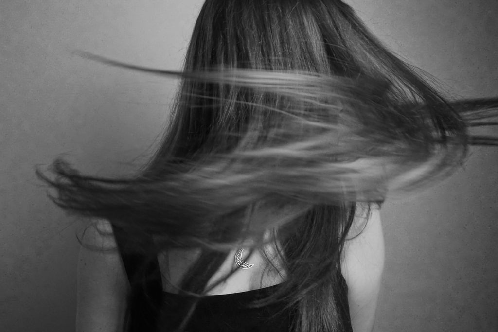Captivating black and white portrait of a woman with flowing hair, captured in a studio.