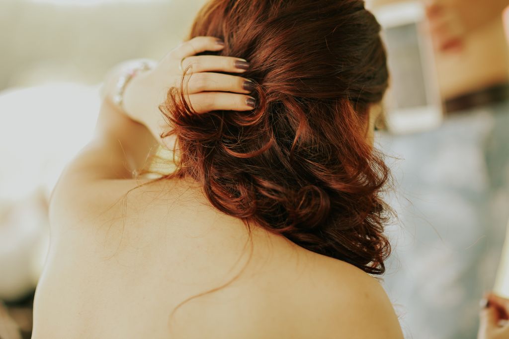 Sophisticated back view of a woman with styled red hair in natural light.