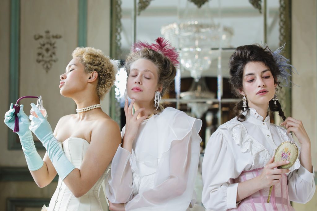Three women in vintage attire pose indoors, exuding elegance and style in a classic setting.